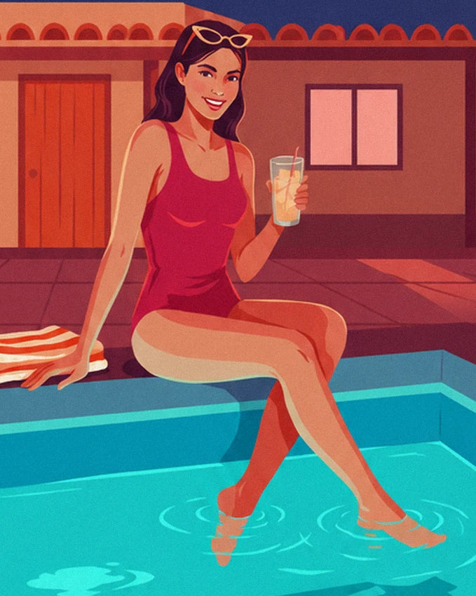 Une femme en maillot rouge, verre à la main et pieds dans l'eau turquoise de la piscine