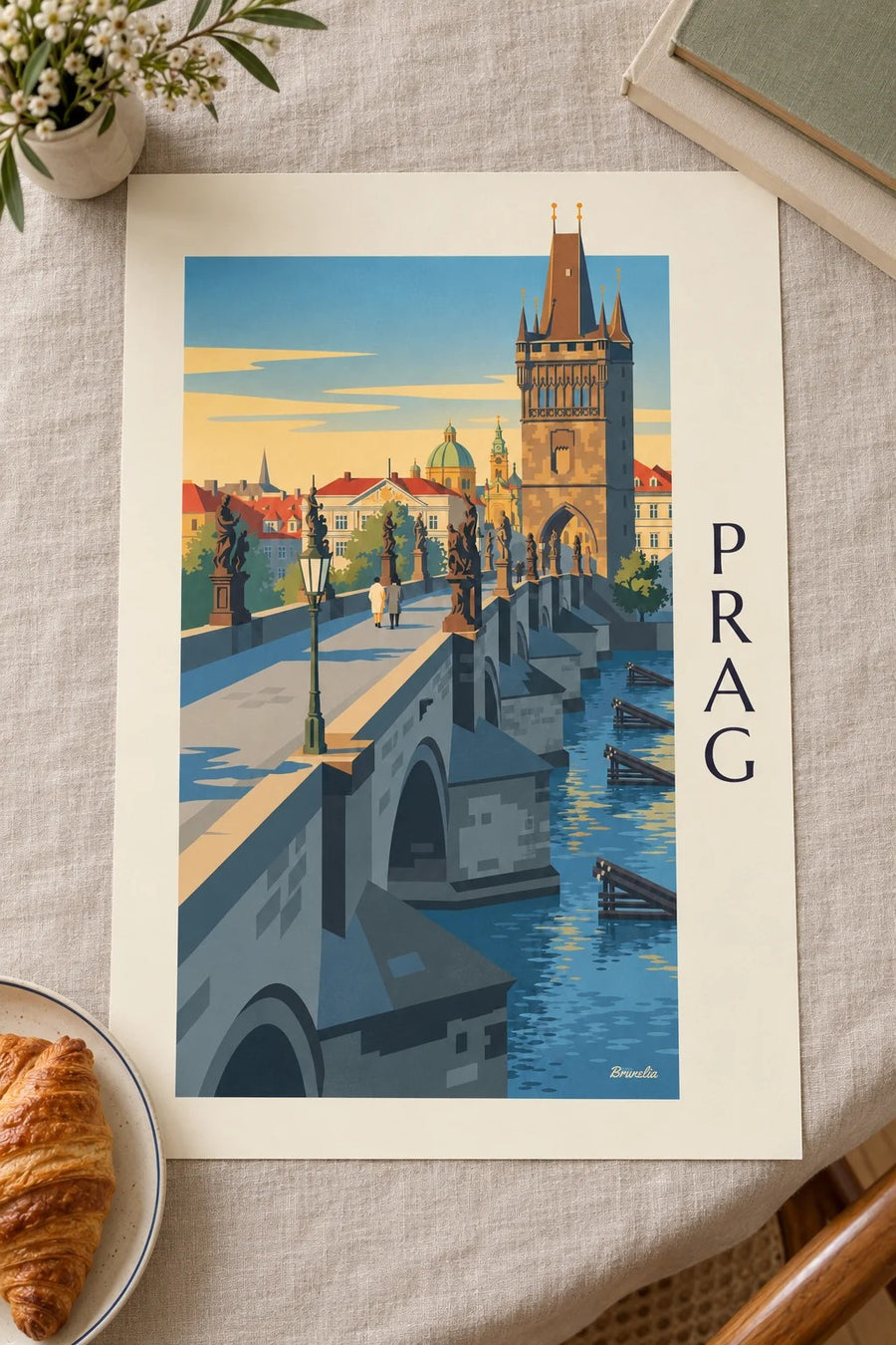 Affisch med Prag, Karlsbron och gotiskt torn över Vltava: liggande på ett bord