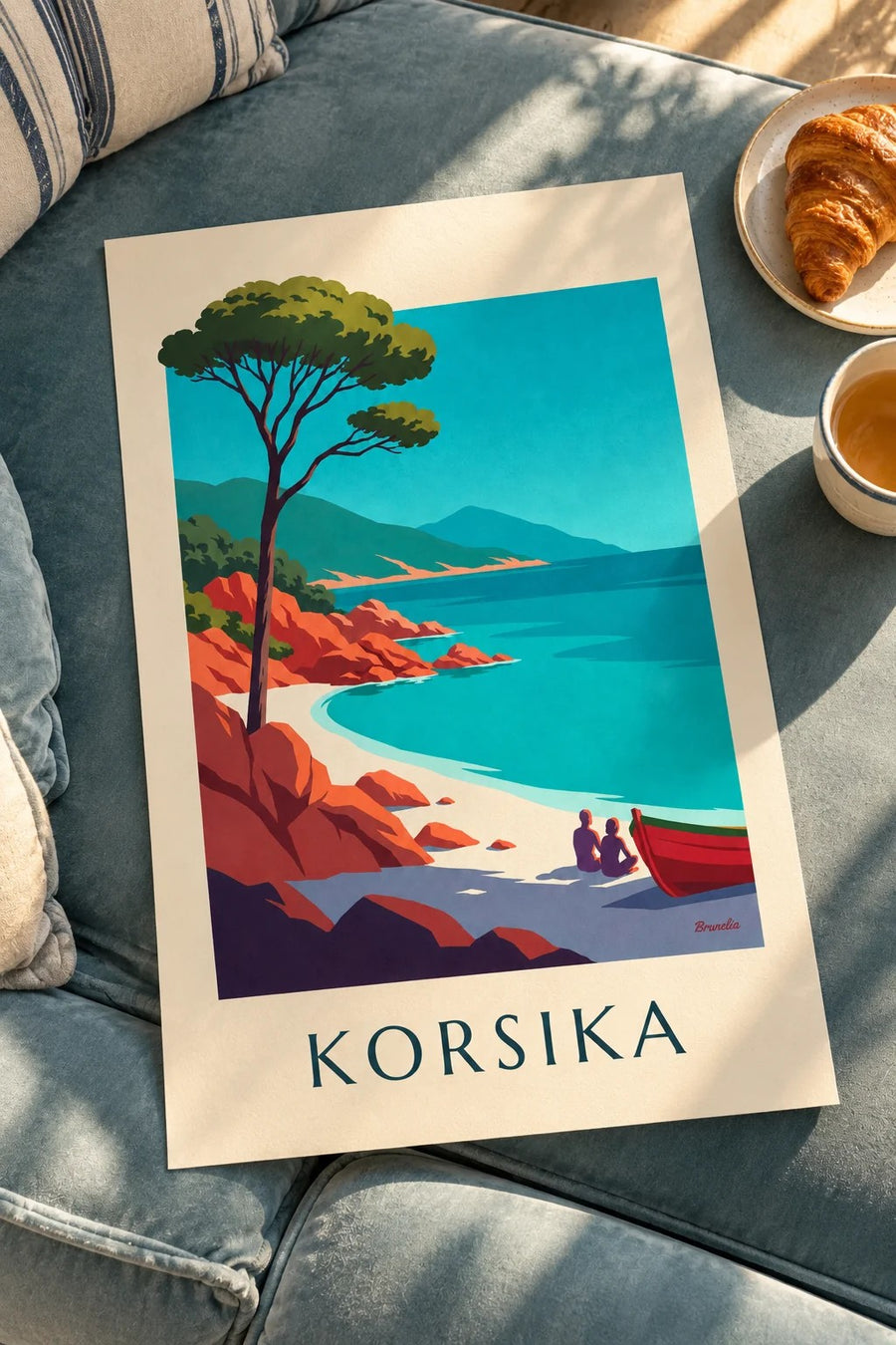 Affisch med korsikansk vik, röd granit och strandpinje: liggande på ett bord